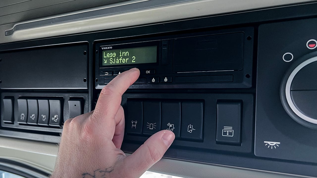 Sjåfør betjener digital fartsskriver i lastebil, som illustrerer Volmax sitt digitale fartsskriverkurs med fokus på korrekt bruk, regelverk og etterlevelse av kjøre- og hviletidsbestemmelser.